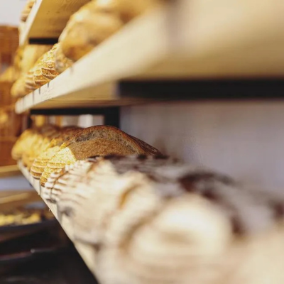 KI generiert: Das Bild zeigt dicht gepackte Regale mit verschiedenen Broten. Der Fokus liegt auf der Vielfalt und Anordnung der Brote in einem Laden oder einer Bäckerei.