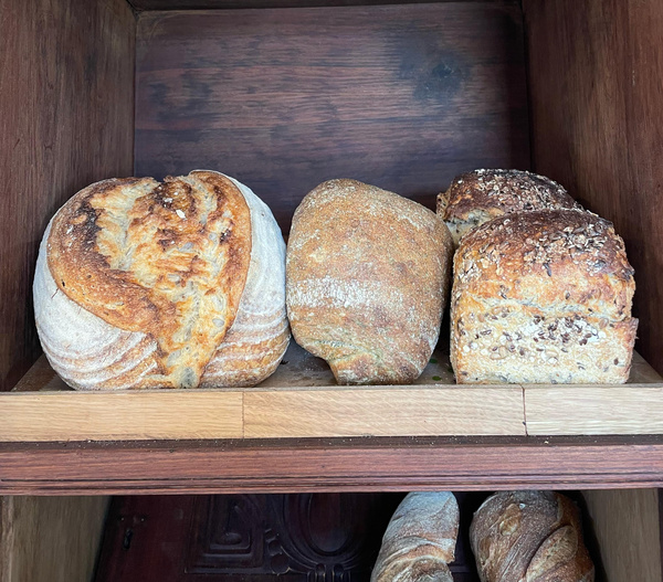 KI generiert: Verschiedene Brotsorten in einem Holzregal ausgestellt.